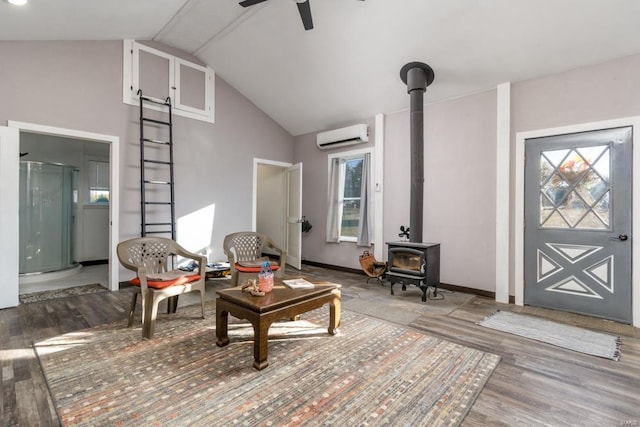 living room featuring a wall unit AC, ceiling fan, a healthy amount of sunlight, hardwood / wood-style flooring, and a wood stove