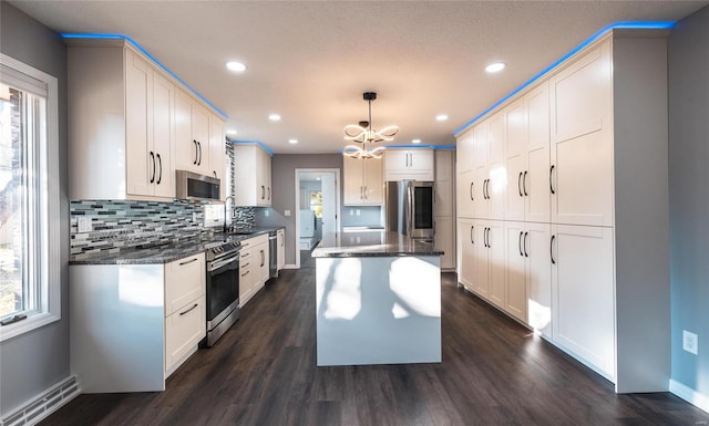 kitchen with a kitchen island, dark hardwood / wood-style floors, stainless steel appliances, sink, and decorative light fixtures