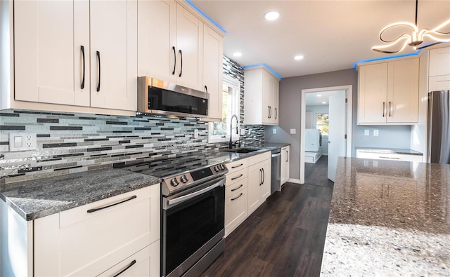 kitchen featuring dark wood-type flooring, hanging light fixtures, sink, white cabinetry, and appliances with stainless steel finishes