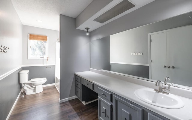 bathroom featuring vanity, toilet, a textured ceiling, and hardwood / wood-style floors