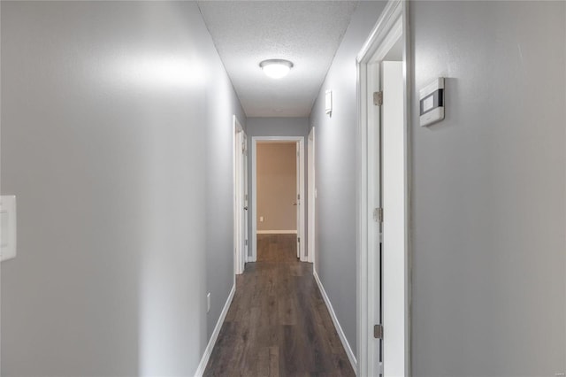 corridor with a textured ceiling and dark hardwood / wood-style flooring