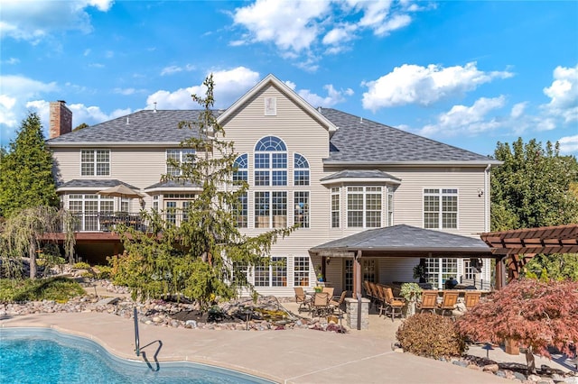 rear view of house featuring a pergola and a patio