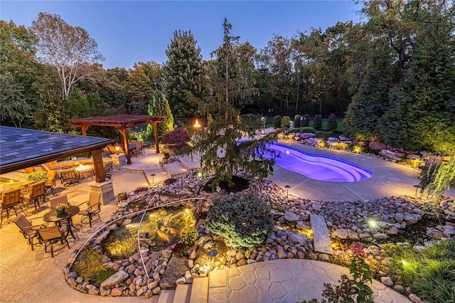 pool at dusk featuring a gazebo, a patio, and a bar