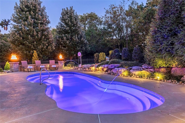 pool at dusk featuring a patio area