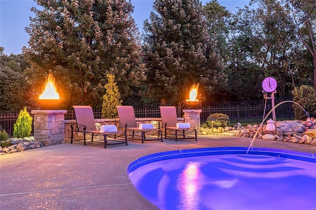 pool at dusk featuring a patio and a fire pit