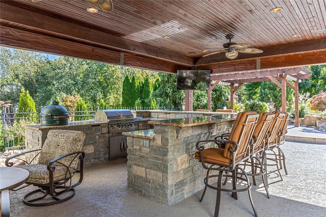 view of patio with a bar, a grill, ceiling fan, and exterior kitchen