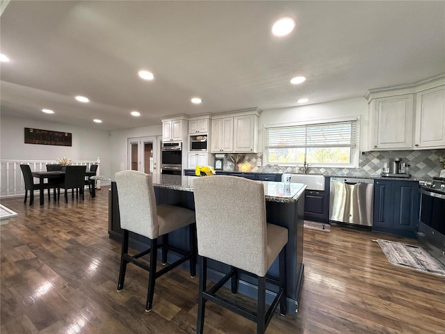 kitchen with appliances with stainless steel finishes, dark stone countertops, white cabinets, and a center island