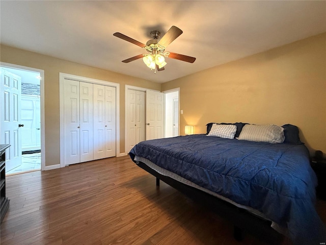 bedroom with ceiling fan, dark wood-type flooring, and multiple closets