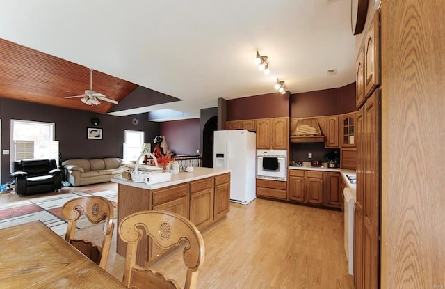 kitchen with white appliances, a kitchen island, light hardwood / wood-style floors, ceiling fan, and lofted ceiling