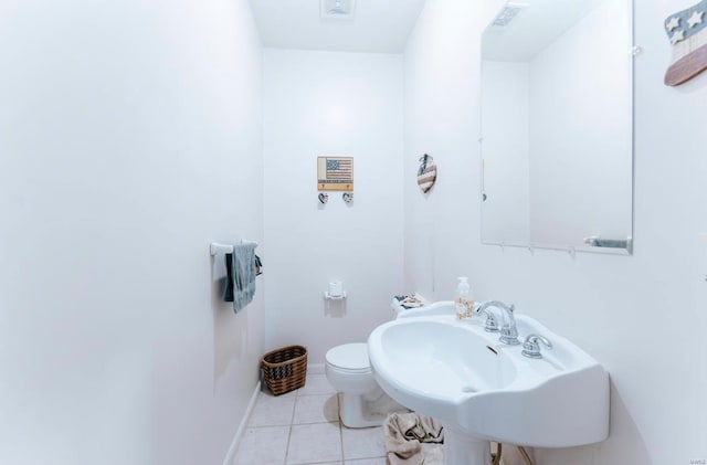 bathroom with toilet, sink, and tile patterned floors