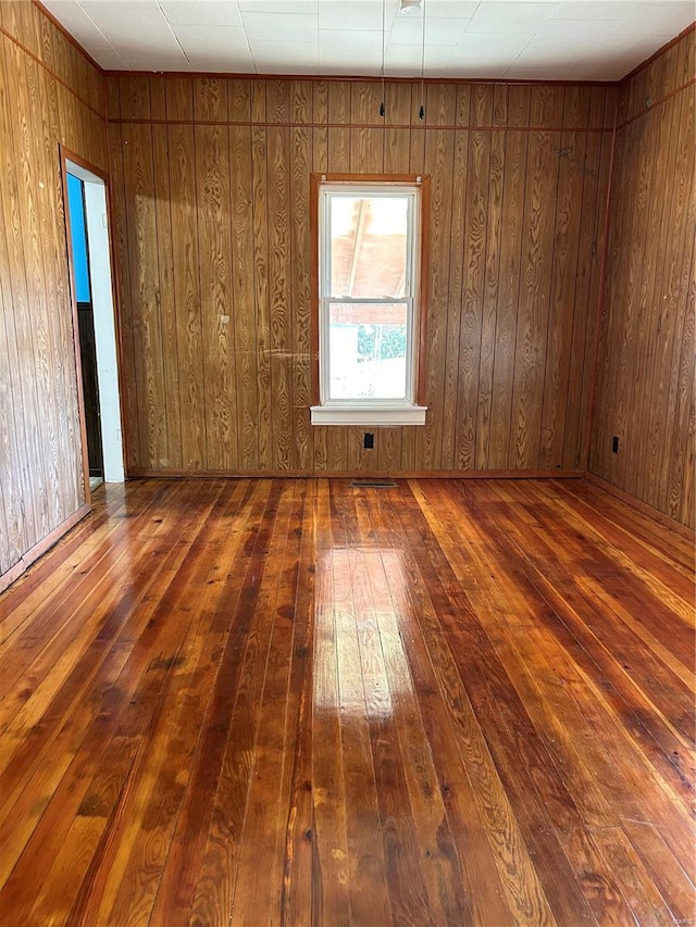 empty room with dark hardwood / wood-style flooring and wooden walls