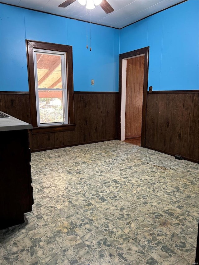 spare room featuring ceiling fan and wooden walls