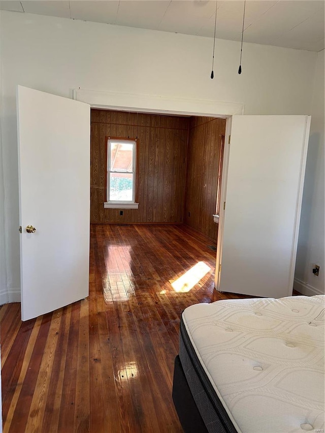 unfurnished bedroom featuring dark hardwood / wood-style flooring and wood walls