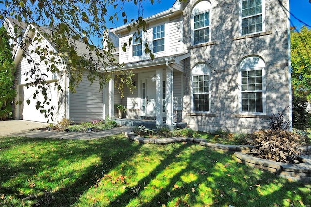 view of front of house featuring a front yard, covered porch, and a garage