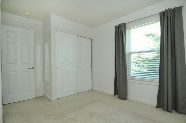 unfurnished bedroom featuring light carpet and a closet