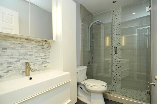 bathroom featuring vanity, decorative backsplash, a shower with shower door, and toilet