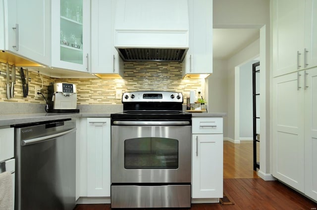 kitchen with stainless steel appliances, dark hardwood / wood-style flooring, premium range hood, and white cabinets