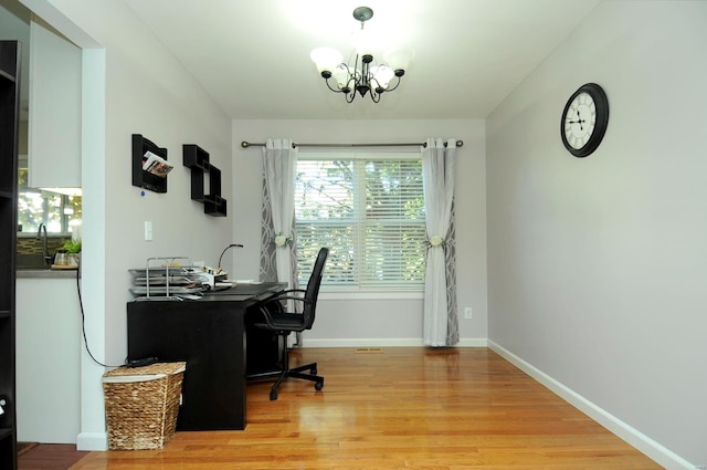 home office with a notable chandelier and light wood-type flooring