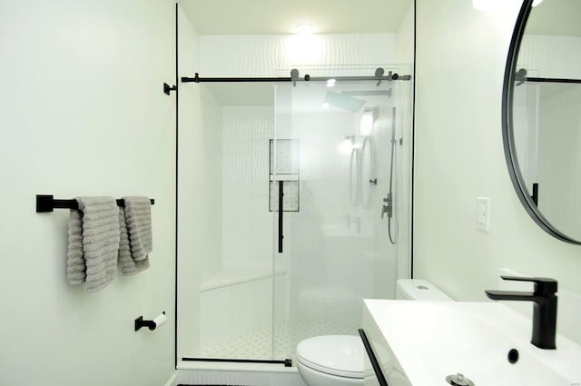 bathroom with toilet, vanity, and a shower with door