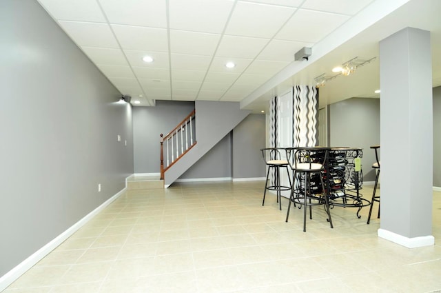 interior space featuring a paneled ceiling, bar area, and light tile patterned floors