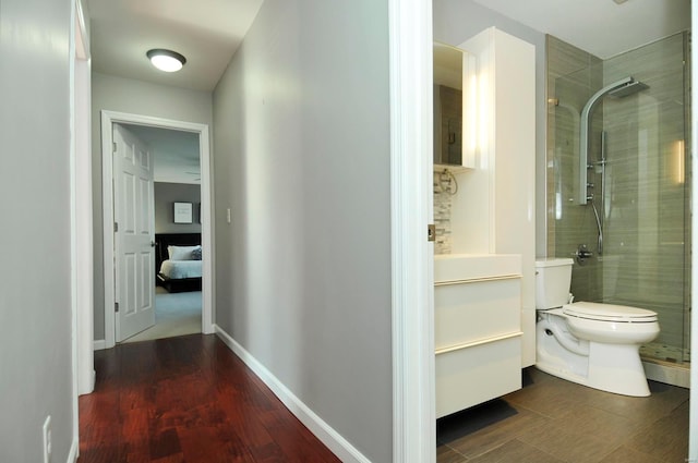 bathroom featuring toilet, vanity, wood-type flooring, and a shower with door