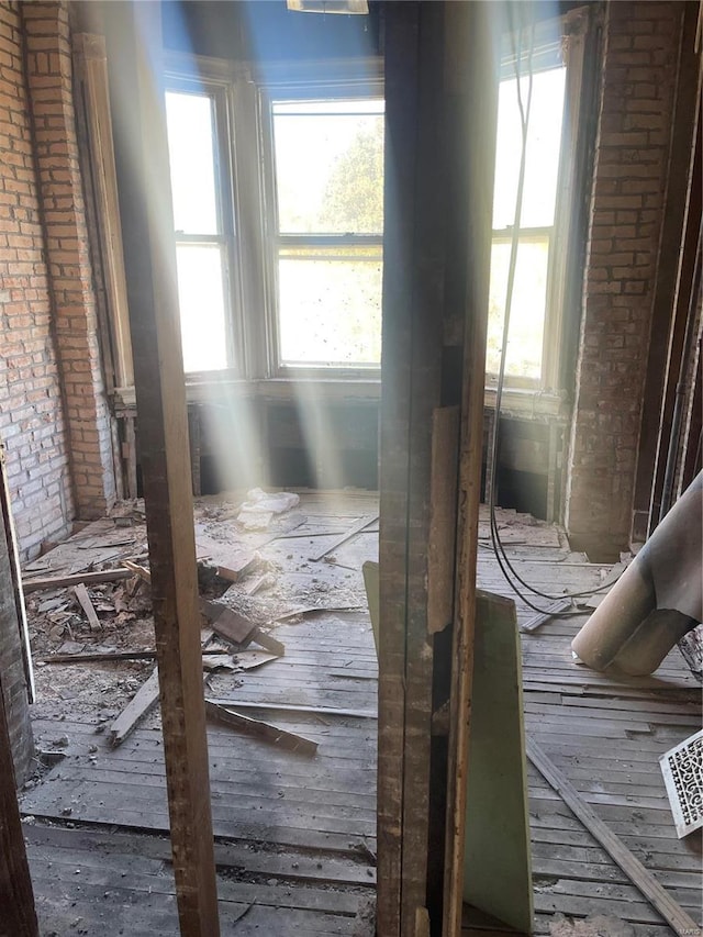 miscellaneous room featuring brick wall and plenty of natural light