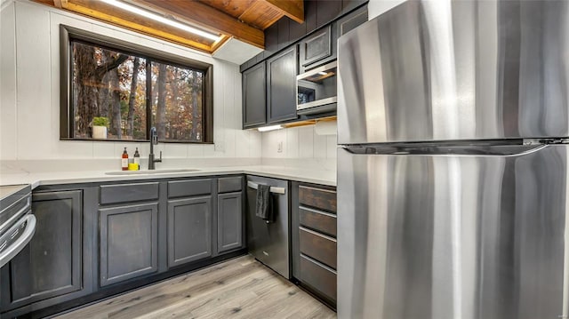 kitchen featuring beam ceiling, wooden ceiling, sink, light hardwood / wood-style floors, and stainless steel appliances