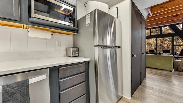 kitchen with light stone counters, stainless steel appliances, and light hardwood / wood-style floors