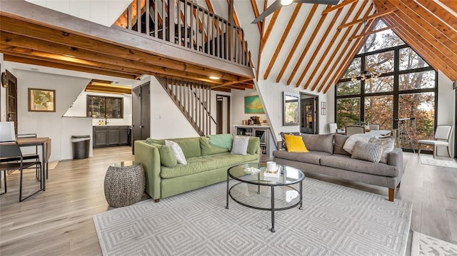 living room with light hardwood / wood-style floors, high vaulted ceiling, beam ceiling, and ceiling fan