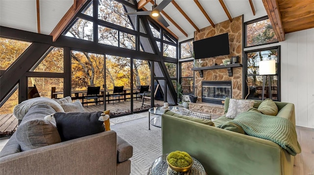 living room with high vaulted ceiling, beamed ceiling, wooden walls, and a stone fireplace