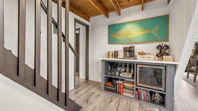 bar with beamed ceiling, light hardwood / wood-style flooring, and wooden walls