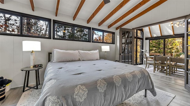 bedroom with lofted ceiling with beams and light hardwood / wood-style floors