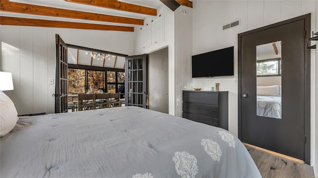 unfurnished bedroom featuring hardwood / wood-style floors, vaulted ceiling with beams, and multiple windows