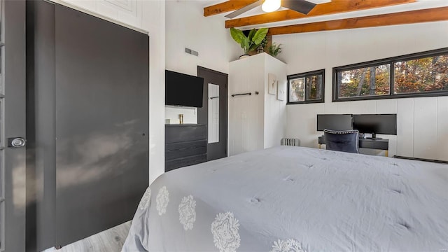 bedroom featuring hardwood / wood-style floors, ceiling fan, beamed ceiling, wooden walls, and high vaulted ceiling