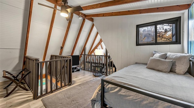 bedroom featuring wooden walls, lofted ceiling with beams, and light wood-type flooring