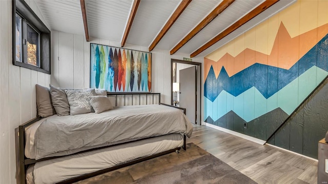 bedroom featuring beam ceiling, wood walls, and wood-type flooring