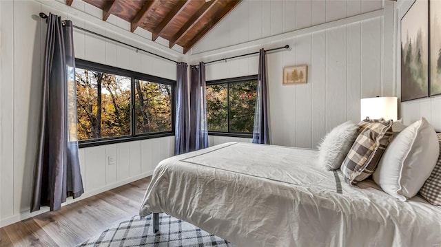 bedroom featuring lofted ceiling with beams, wood ceiling, light wood-type flooring, and wood walls