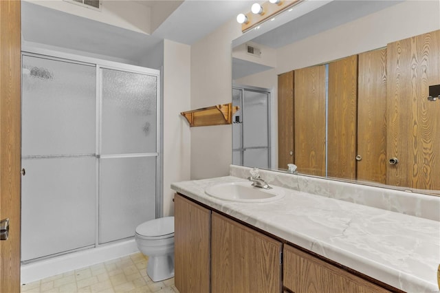 bathroom featuring vanity, a shower with shower door, and toilet