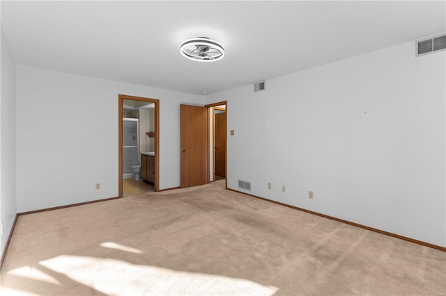 unfurnished bedroom featuring light carpet and ensuite bath