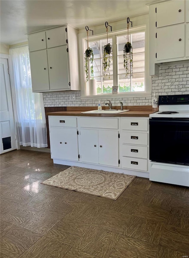 kitchen with decorative backsplash, sink, electric range, decorative light fixtures, and white cabinets