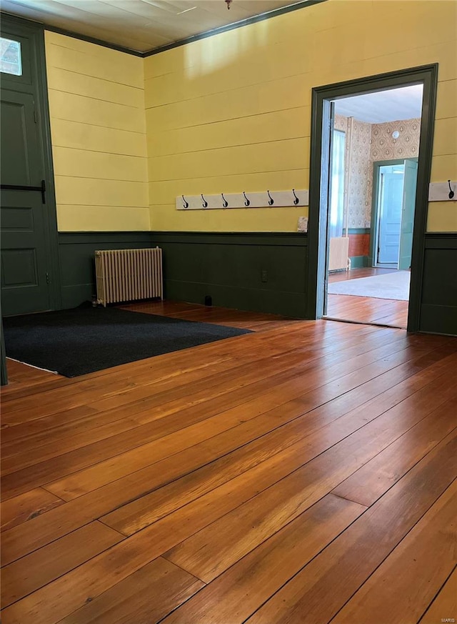 interior space featuring radiator heating unit, wooden walls, and wood-type flooring