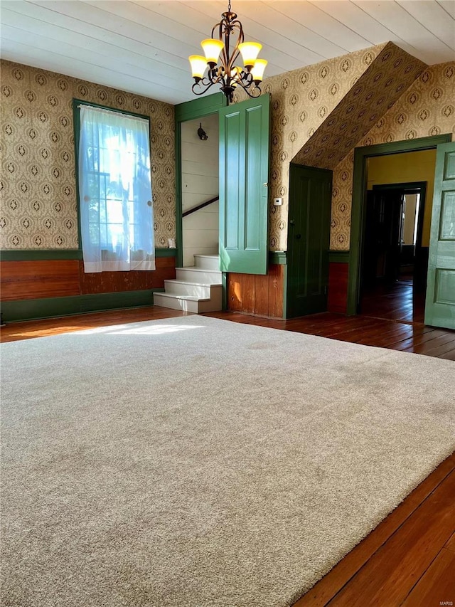 spare room featuring wooden ceiling, dark wood-type flooring, an inviting chandelier, vaulted ceiling, and wooden walls