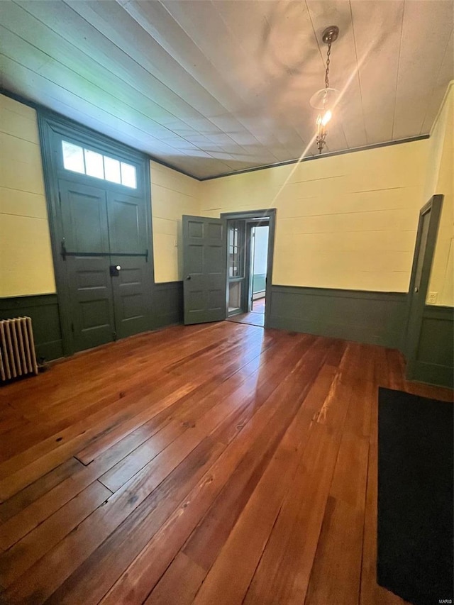 foyer with dark hardwood / wood-style floors, radiator, and wood walls