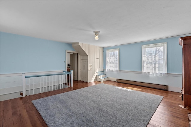 empty room with dark wood-type flooring and a baseboard heating unit