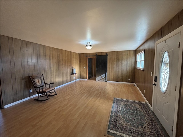 entrance foyer with wooden walls, a barn door, and light hardwood / wood-style flooring