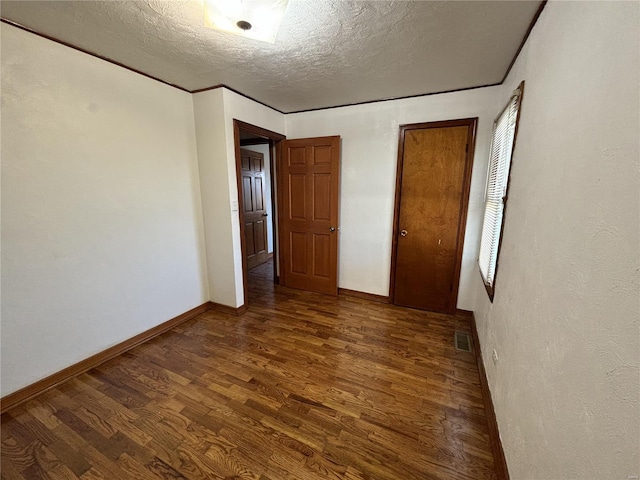 unfurnished bedroom featuring a textured ceiling and dark hardwood / wood-style floors