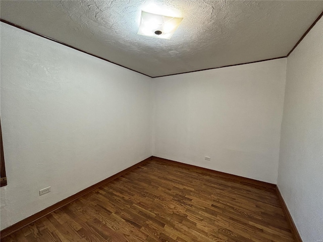 unfurnished room featuring dark wood-type flooring and a textured ceiling