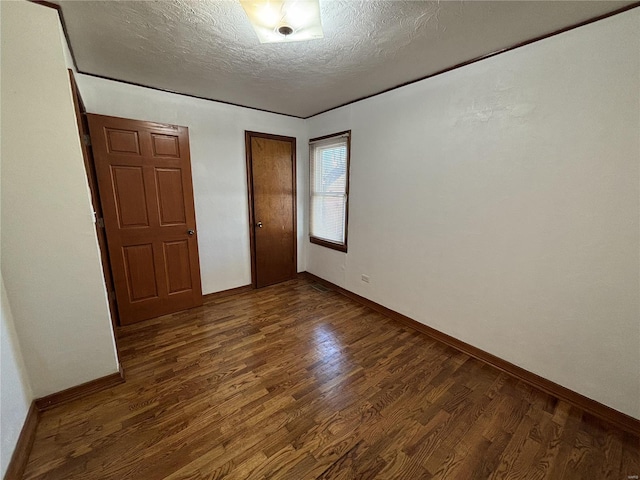 unfurnished bedroom featuring a textured ceiling and dark hardwood / wood-style flooring