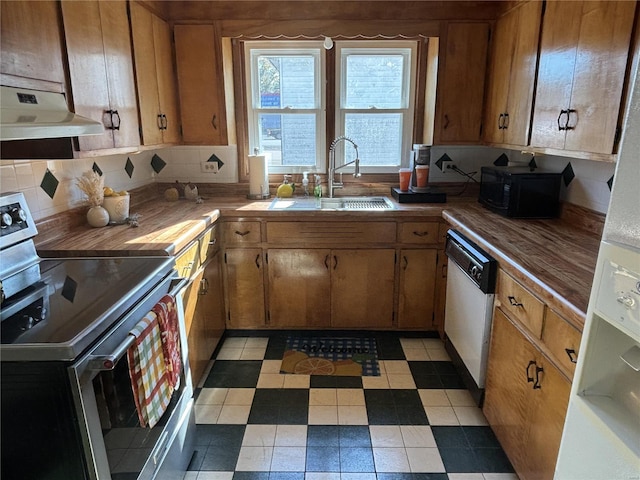 kitchen with appliances with stainless steel finishes, sink, decorative backsplash, and wooden counters