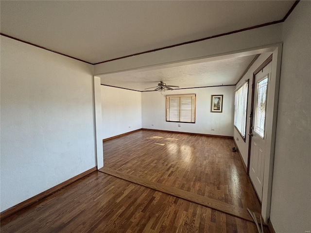 spare room with dark wood-type flooring, ceiling fan, and crown molding